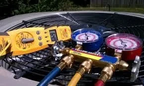 Manifold gauge set and multimeter on a condenser unit during an AC diagnostic call